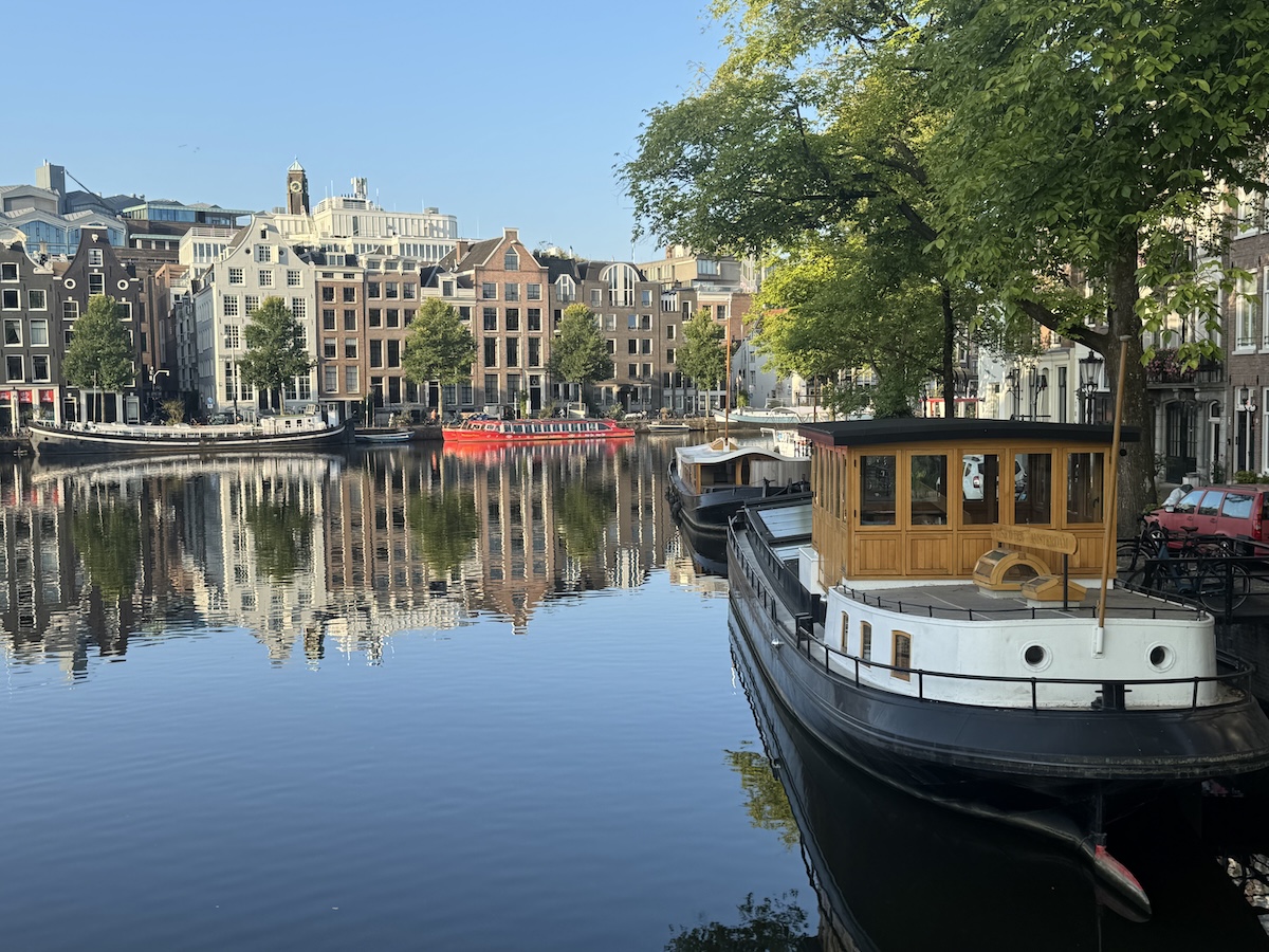 Houseboat on a calm canal in Amsterdam with historic buildings in the background