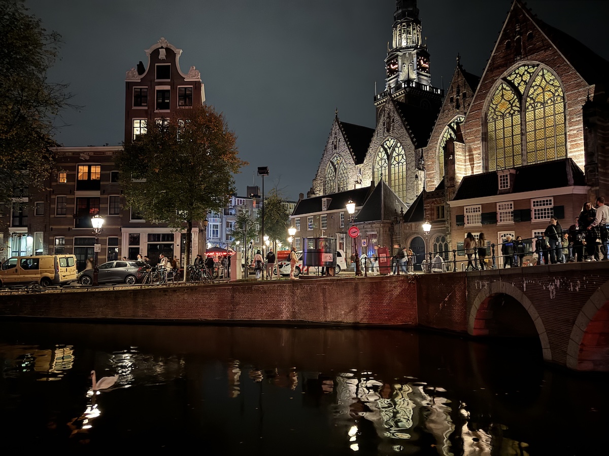 Oude Kerk in Amsterdam illuminated at night beside a canal, an atmospheric stop on a haunted Amsterdam ghost walk.