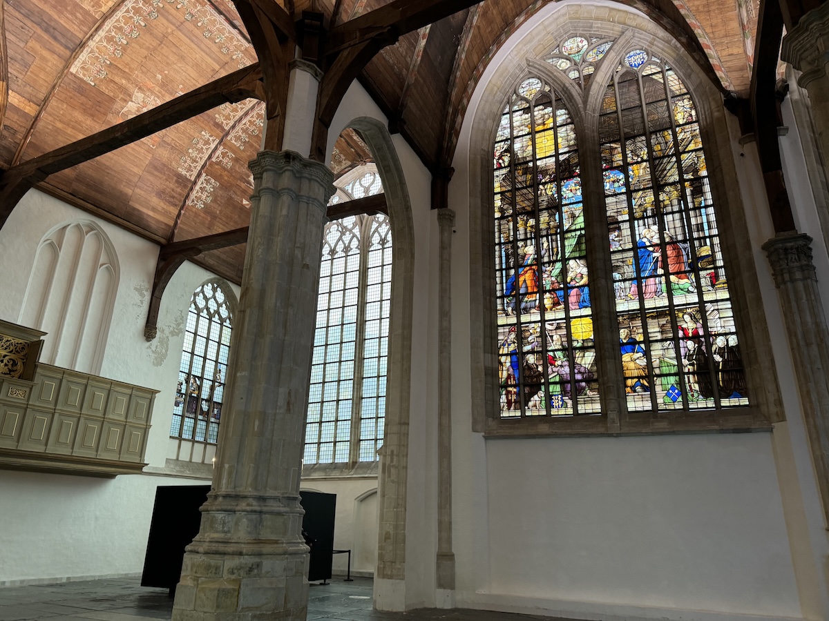 Interior of the Oude Kerk in Amsterdam with stained glass windows and wooden ceiling linked to old ghost stories