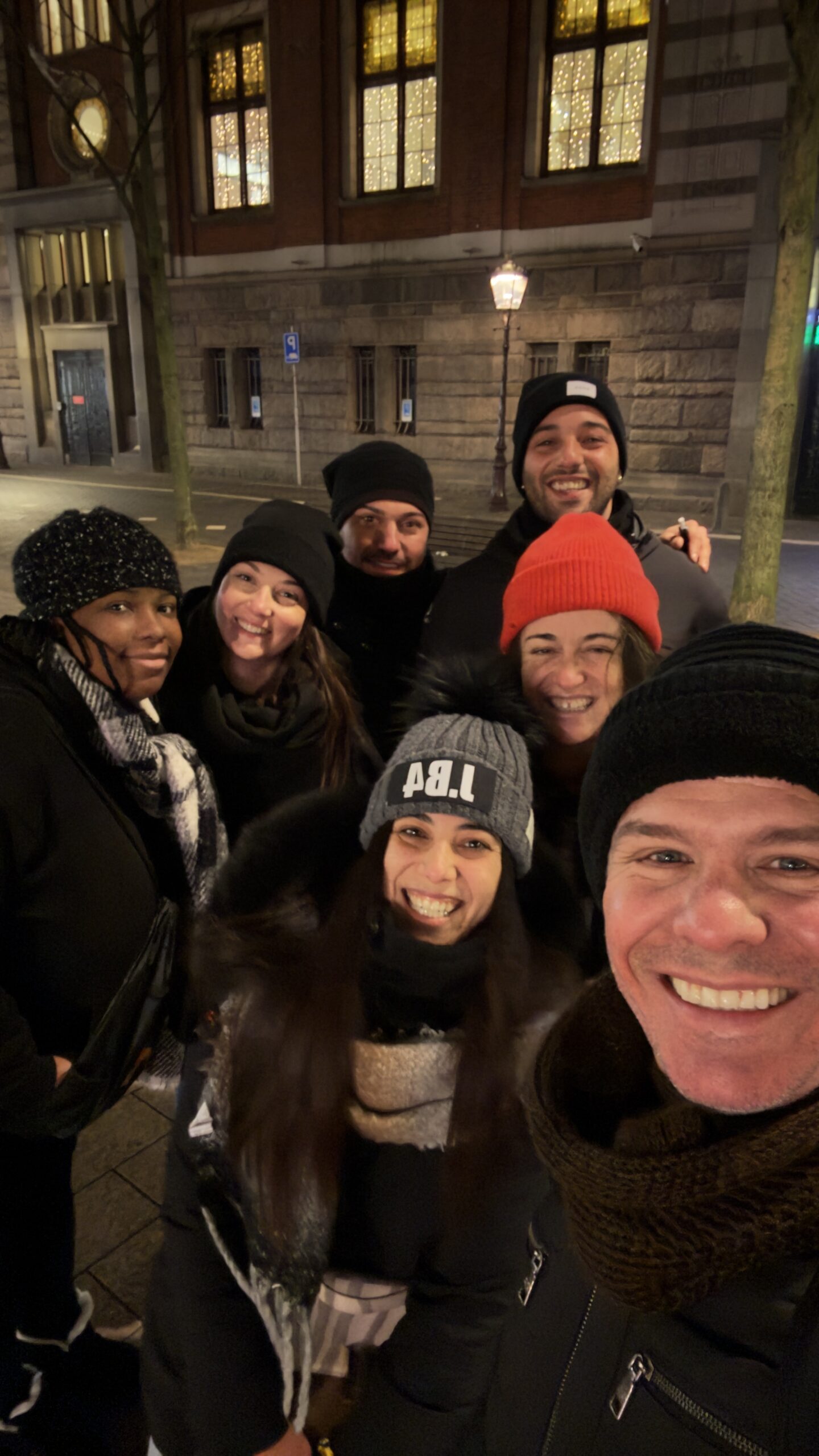 Group of visitors smiling during a Red Light District walking tour in Amsterdam at night