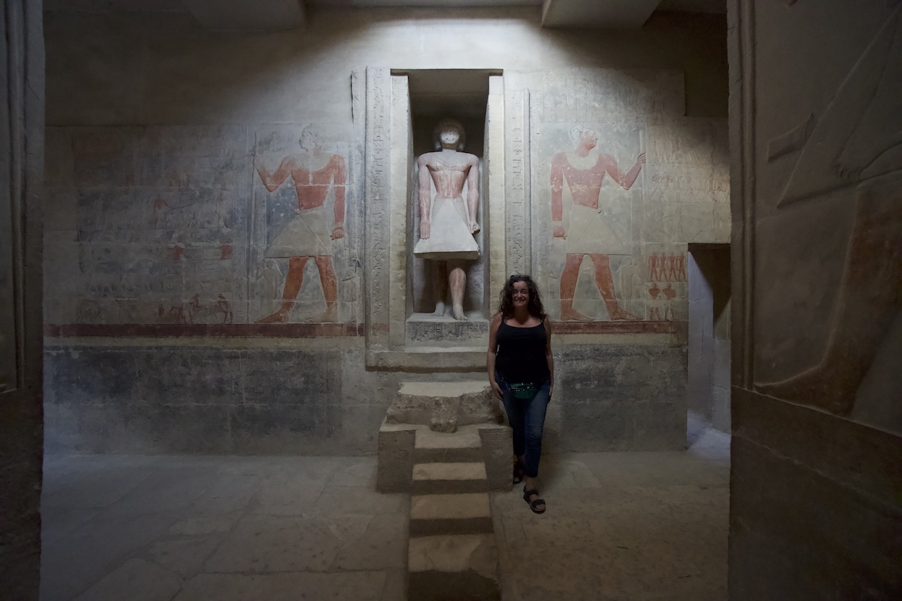 Interior of Saqqara Mereruka tomb with painted walls and doorway and Pilar standing in there