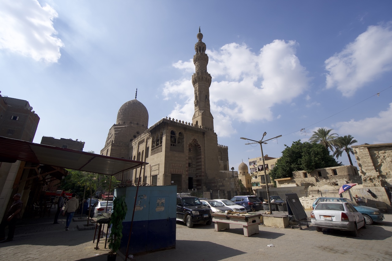 Sultan Qaitbay Mosque in Cairo’s City of the Dead with cars and local street activity in the foreground