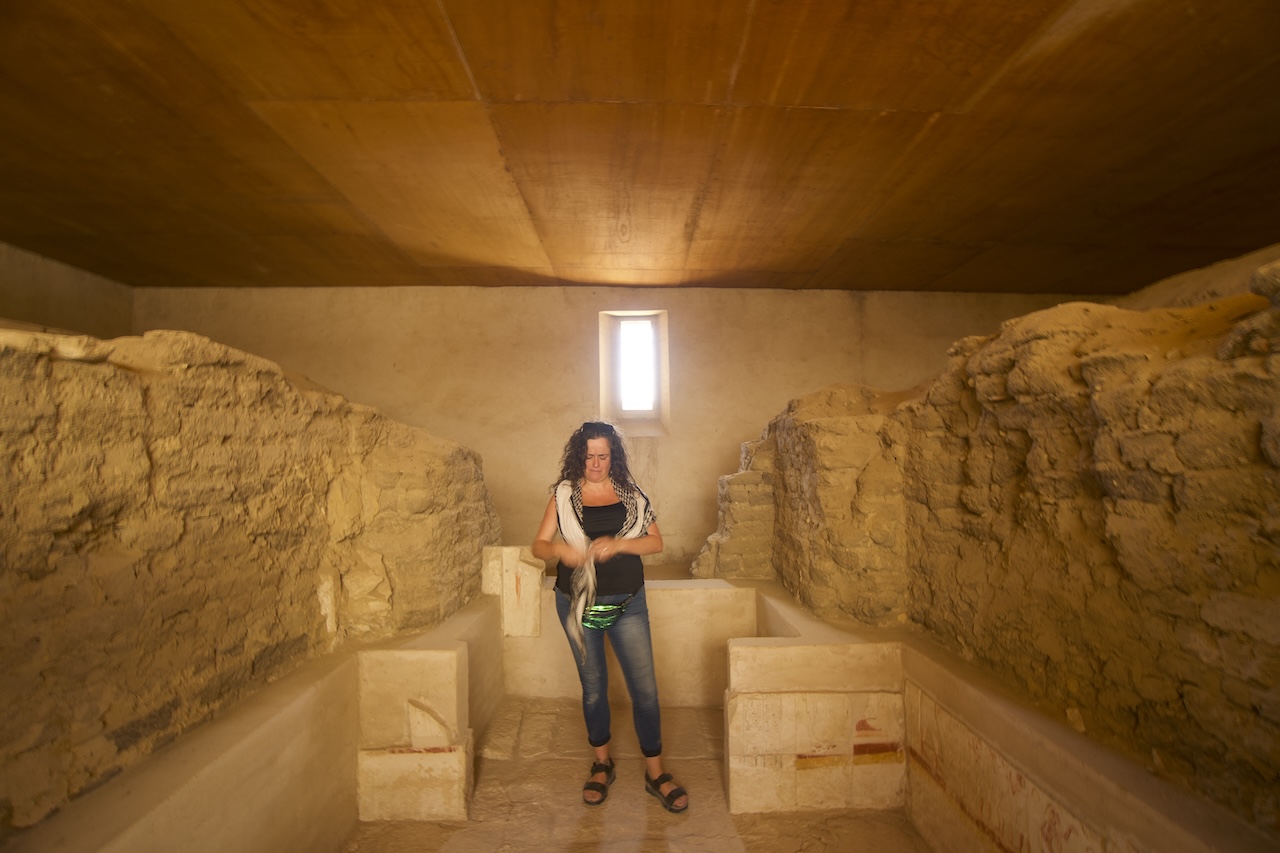Inside ancient burial chamber in Saqqara with stone benches and Pilar