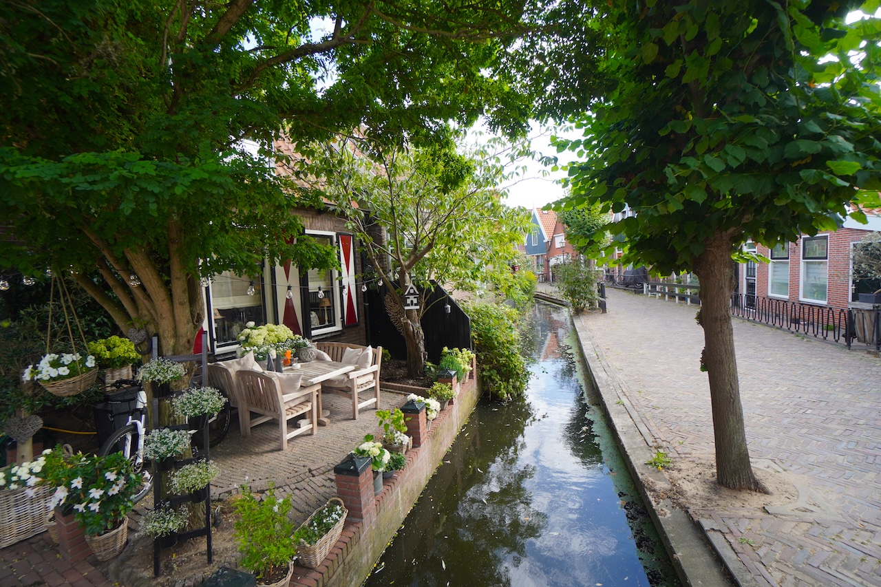 Quiet canal lined with traditional houses, trees and flowers in Volendam